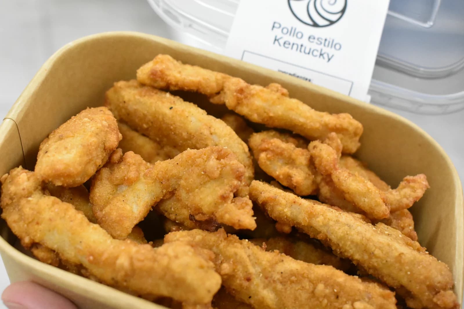 Fingers de pollo crujiente estilo Kentucky en un cuenco de cartón de AriMar