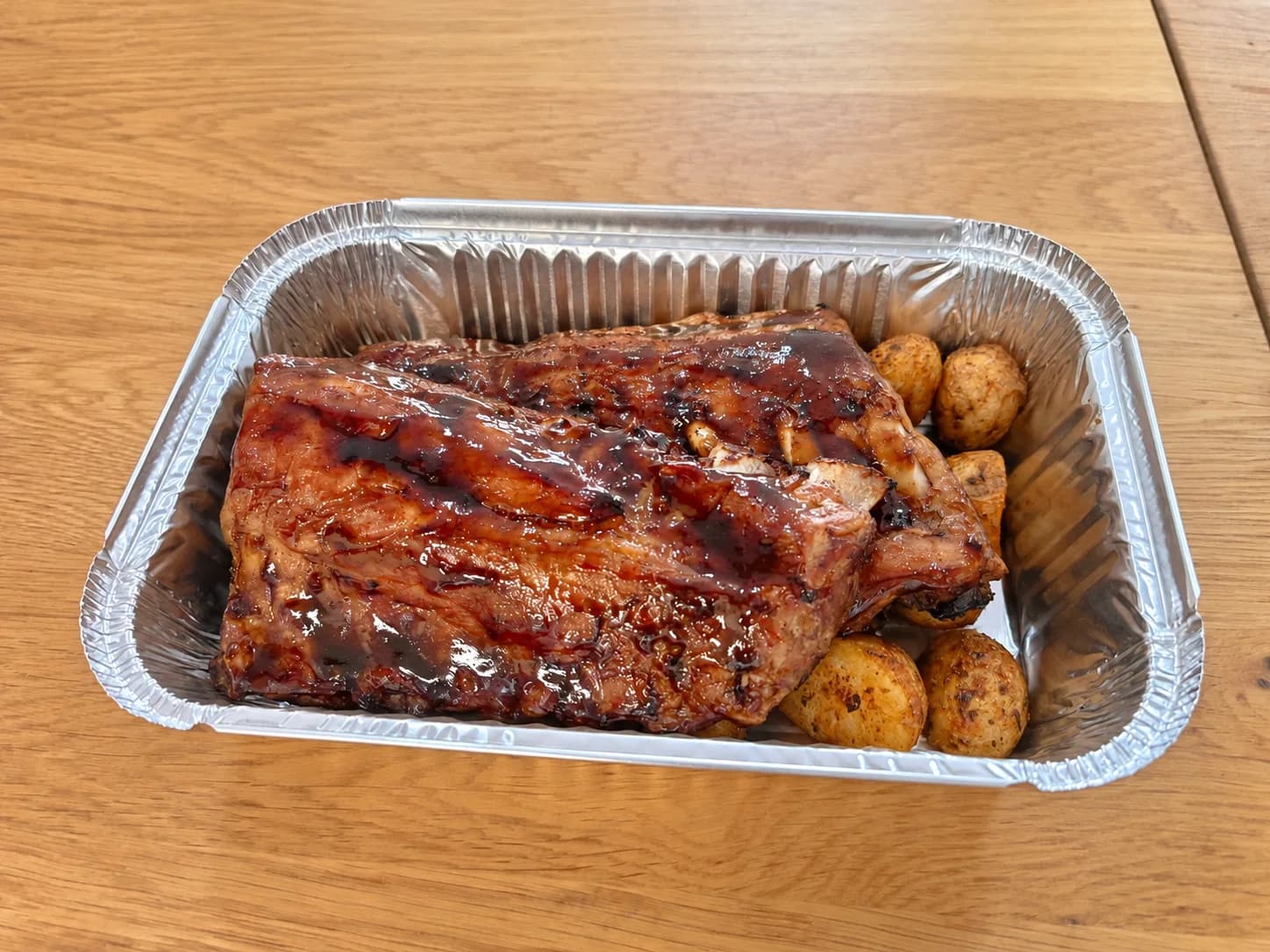 Costillas glaseadas de AriMar presentadas sobre papas asadas